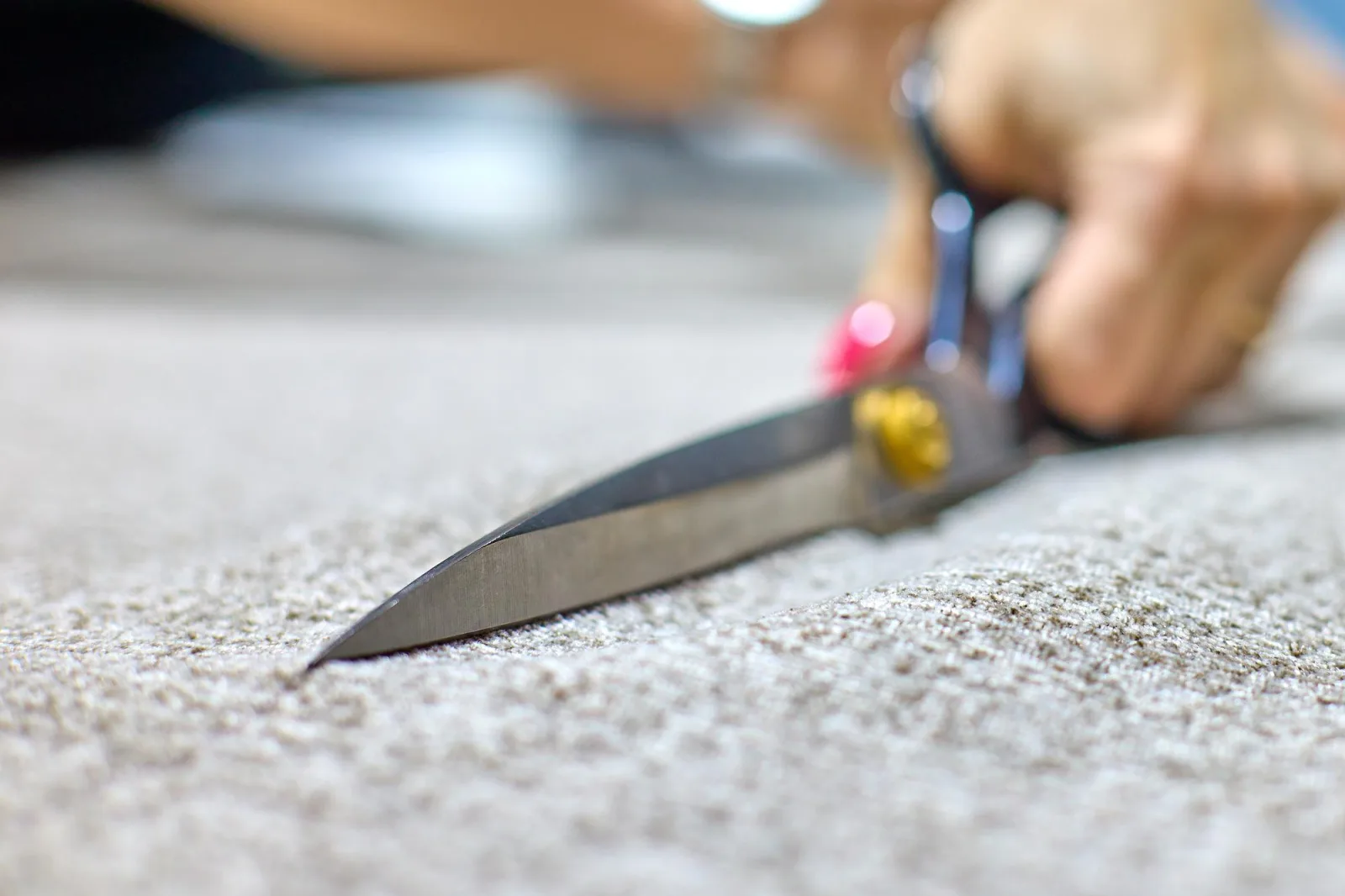 Hands of a dressmaker with a bright manicure cut fabric with scissors