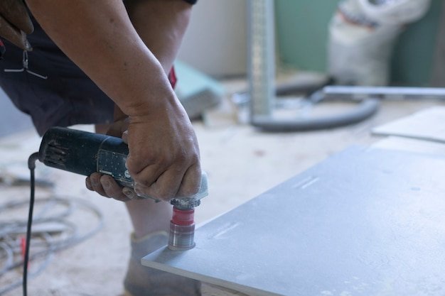 Hands of latin worker drilling holes in tile