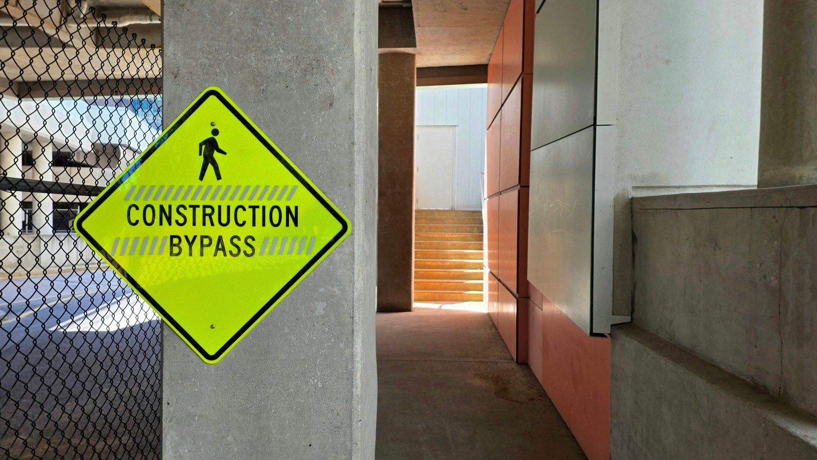 Yellow construction bypass sign on concrete pillar