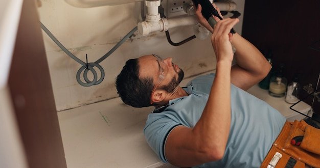 Man plumber and tools for kitchen sink pipe and search for leak problem solving and fix in home Person handyman and check for water drain and solution on floor for maintenance at apartment