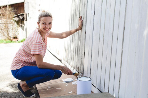 Portrait of smiling woman painting wooden wall