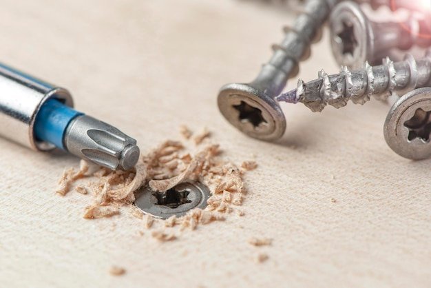 Screw the screw into the board furniture production a screwdriver twists a selftapping screw into a ...