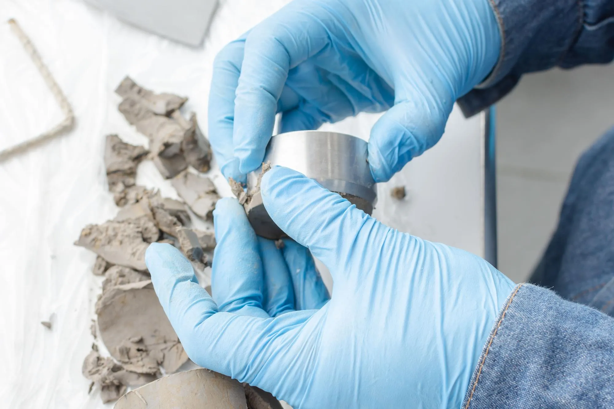 Top view of hands with blue latex gloves holding a metallic piece