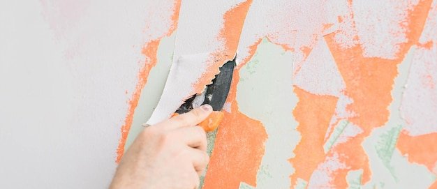 Young man using spatula and plastering of wall with white fresh finishing putty Closeup Repair work of home Empty place for text Side view