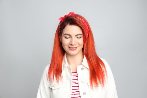 Young woman with bright dyed hair on grey background