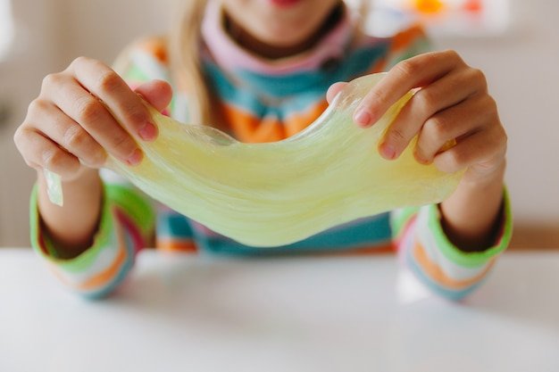 The child stretches the mucus to the sides. Children's hands are playing slime. Making slime. Copyspace. Selective focus. Layout for text.