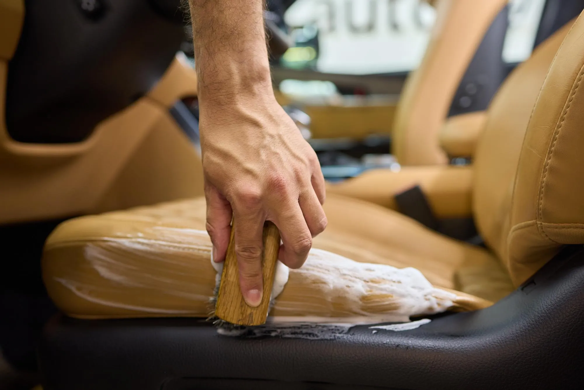 Clean leather car seats with brush and plastic cover for luxury interior maintenance and hygiene