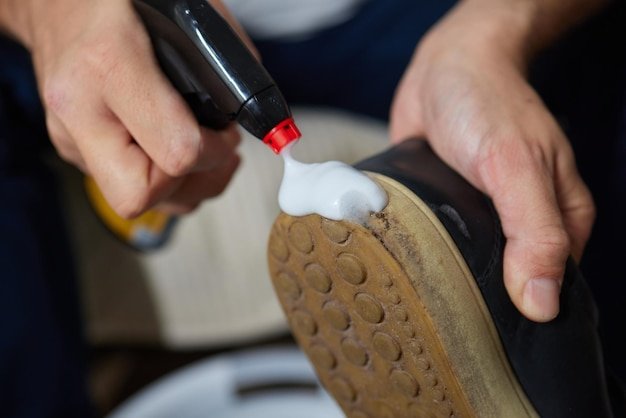 Cleaning suede sneakers A worker in a shoe workshop cleans a pile of shoes