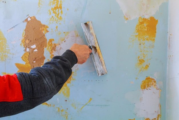 Close-up of cropped hand scraping paint on wall