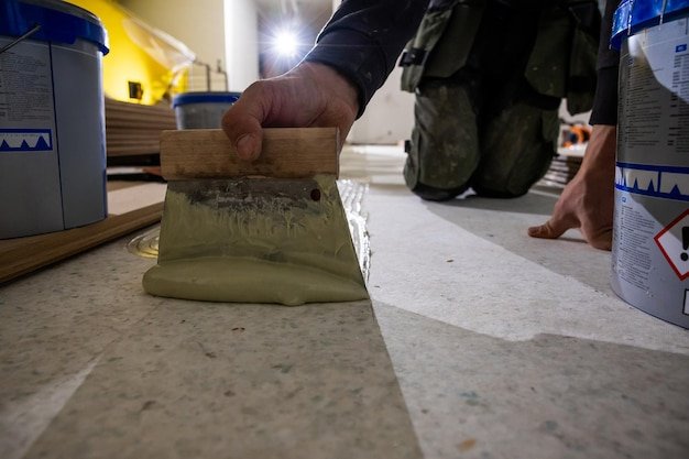 Close Up of Worker Applying Adhesive for Wooden Floor Installation