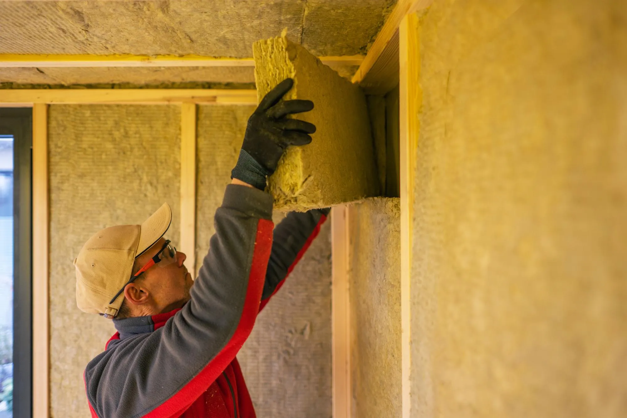 Contractor Installing Mineral Wool Inside Garden Shed Walls