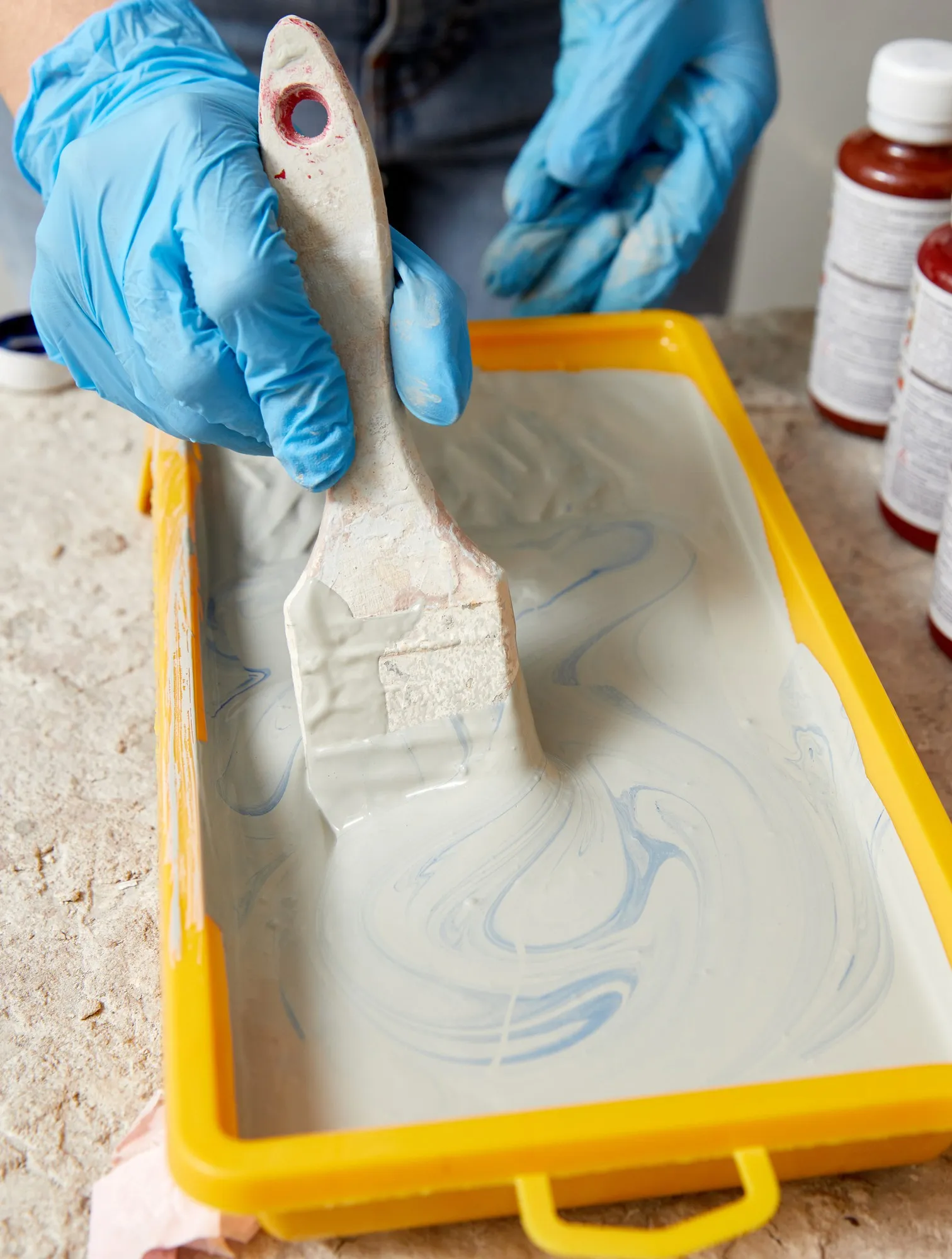 Cropped view of hand wearing gloves using paint brush and paint