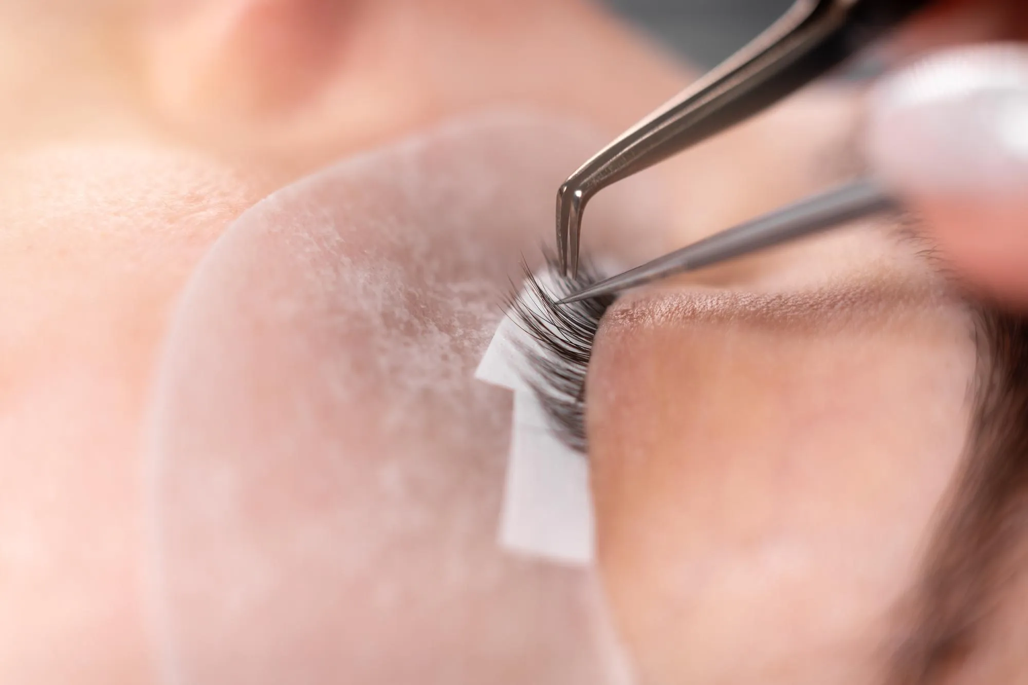 eyelash extension procedure closeup of masters tool Tweezers spread sparse eyelashes preparation for extension