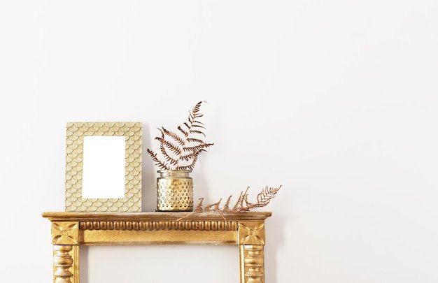 Golden frame and dried plants  on white wall