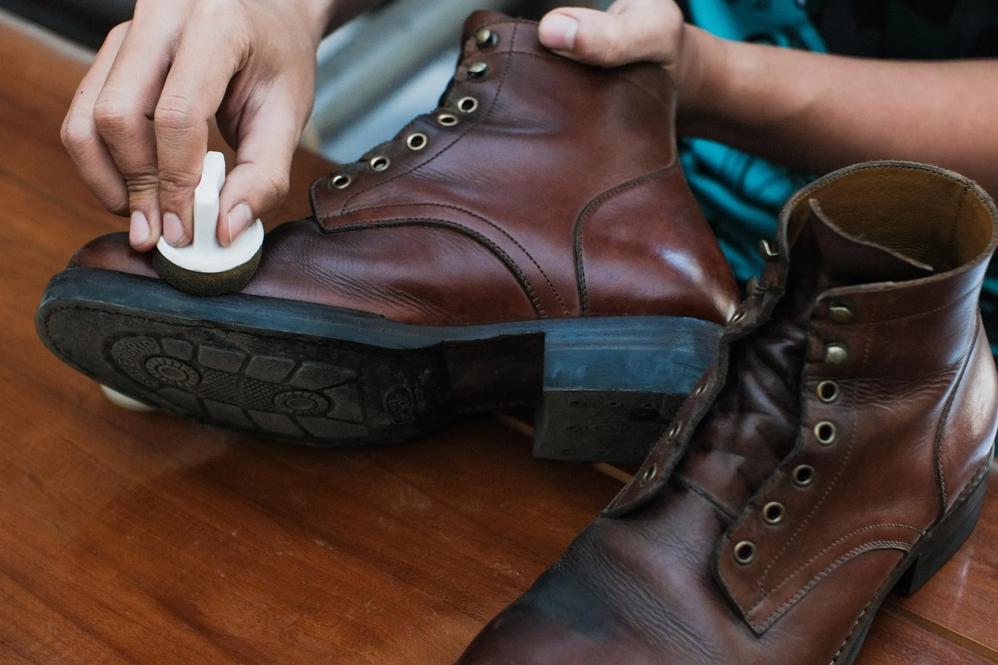 a person is applying a cream to a pair of brown leather boots