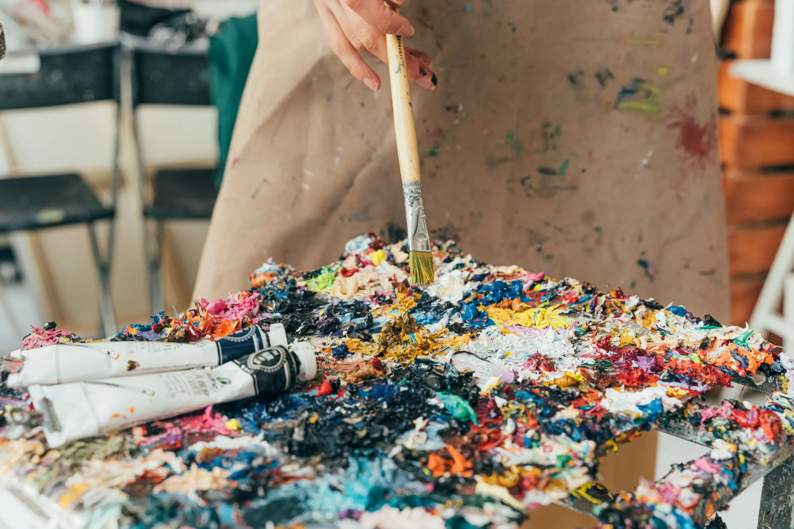 Vibrant paint palette with brush and tubes in an artist's studio setting.