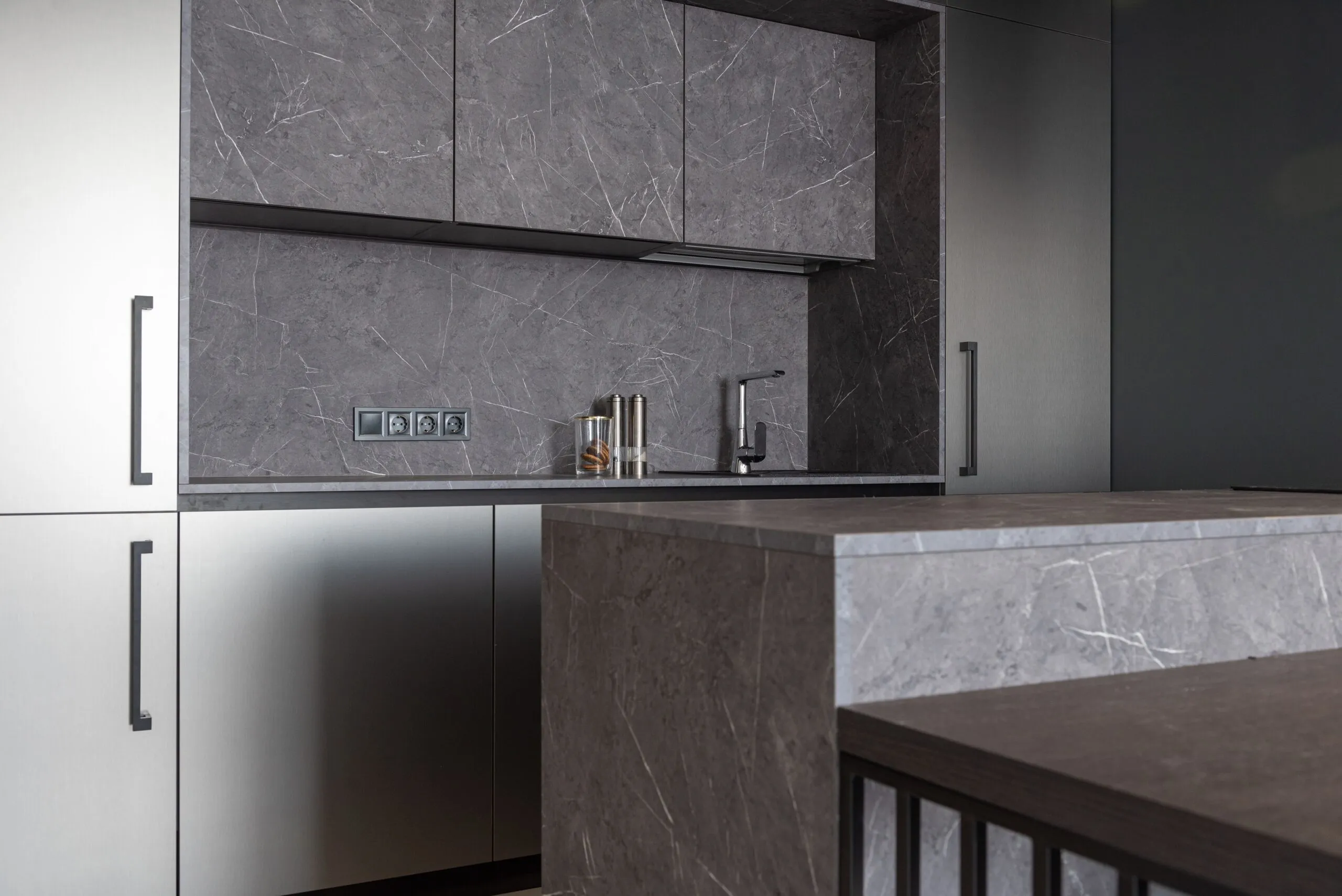 Interior of contemporary kitchen with minimalist gray furniture and counter in residential apartment