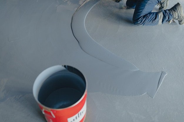 The worker applies gray epoxy resin to the new floor