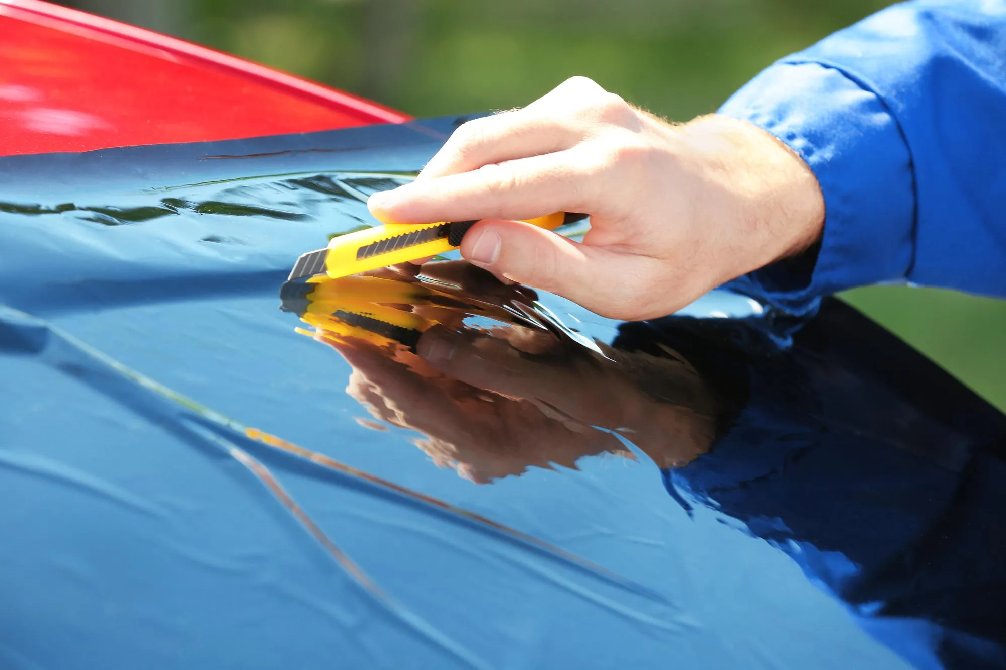 Worker applying tinting foil onto car window