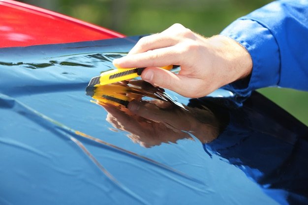 Worker applying tinting foil onto car window
