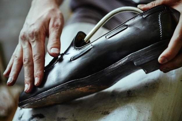 Young caucasian man repairing old male leather shoes.