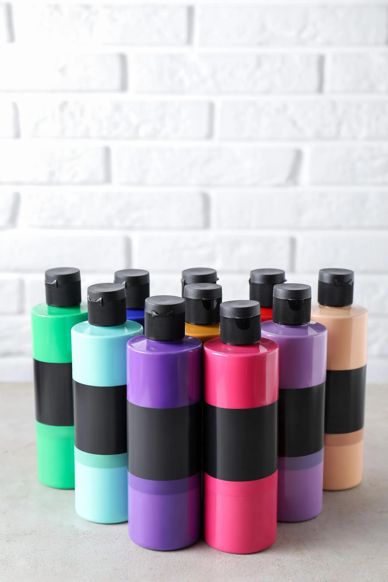 Acrylic paints of different colors in bottles on light table