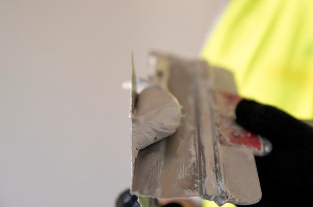 Builder with a spatula in his hands stirs the plaster mixture on a spatula close up