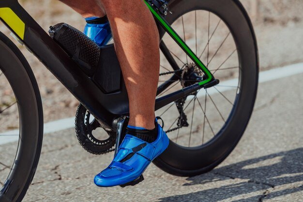 Close up photo of an active triathlete in sportswear and with a protective helmet riding a bicycle. Selective focus.