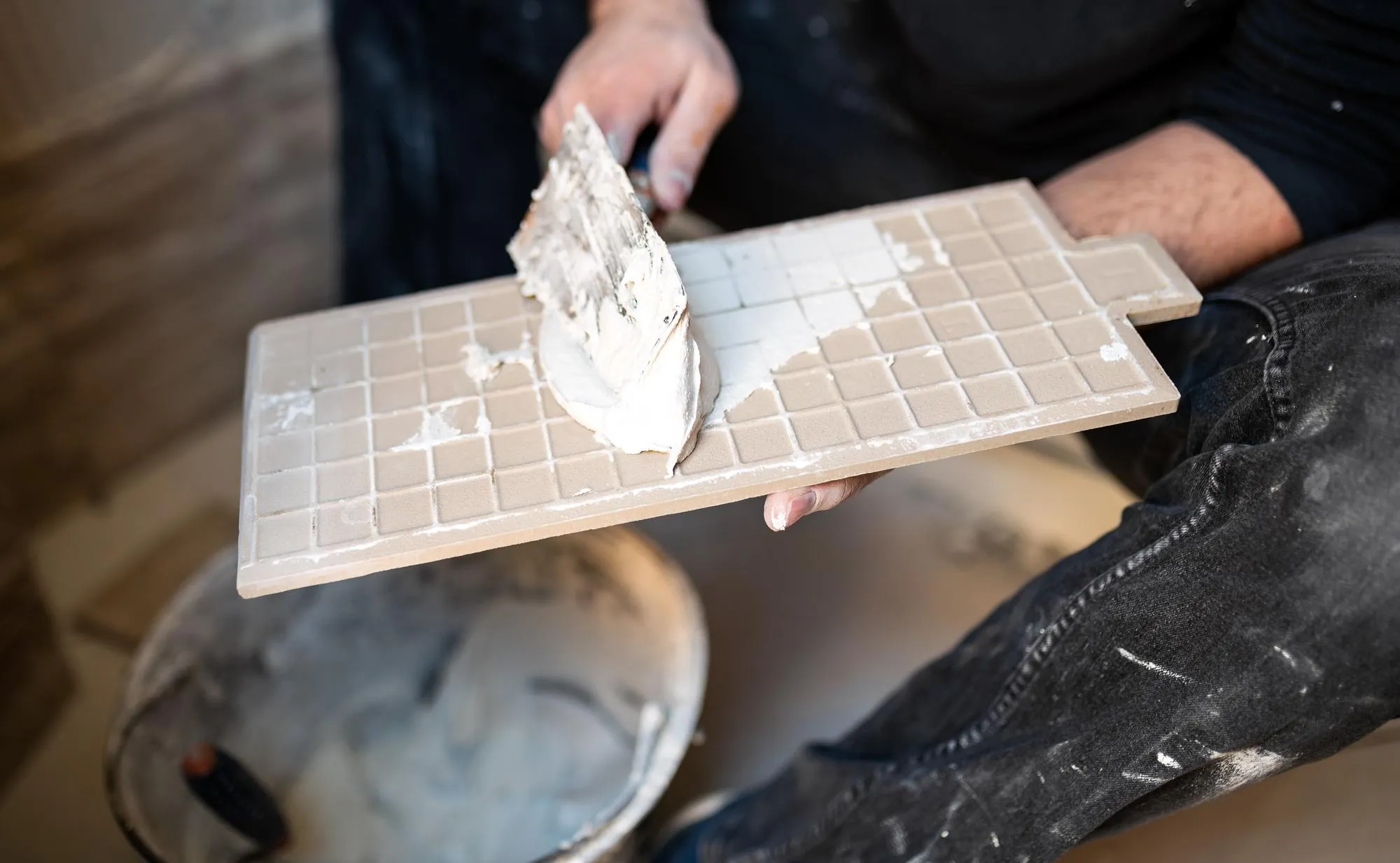 Closeup of a tiler applying adhesive to a tile