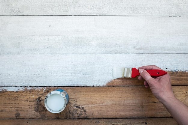 Cropped hand of man painting wooden floor