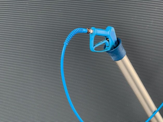 A highpressure car washer gun with a sturdy nozzle and flexible hose is positioned upright designed for efficient cleaning of vehicles outdoors