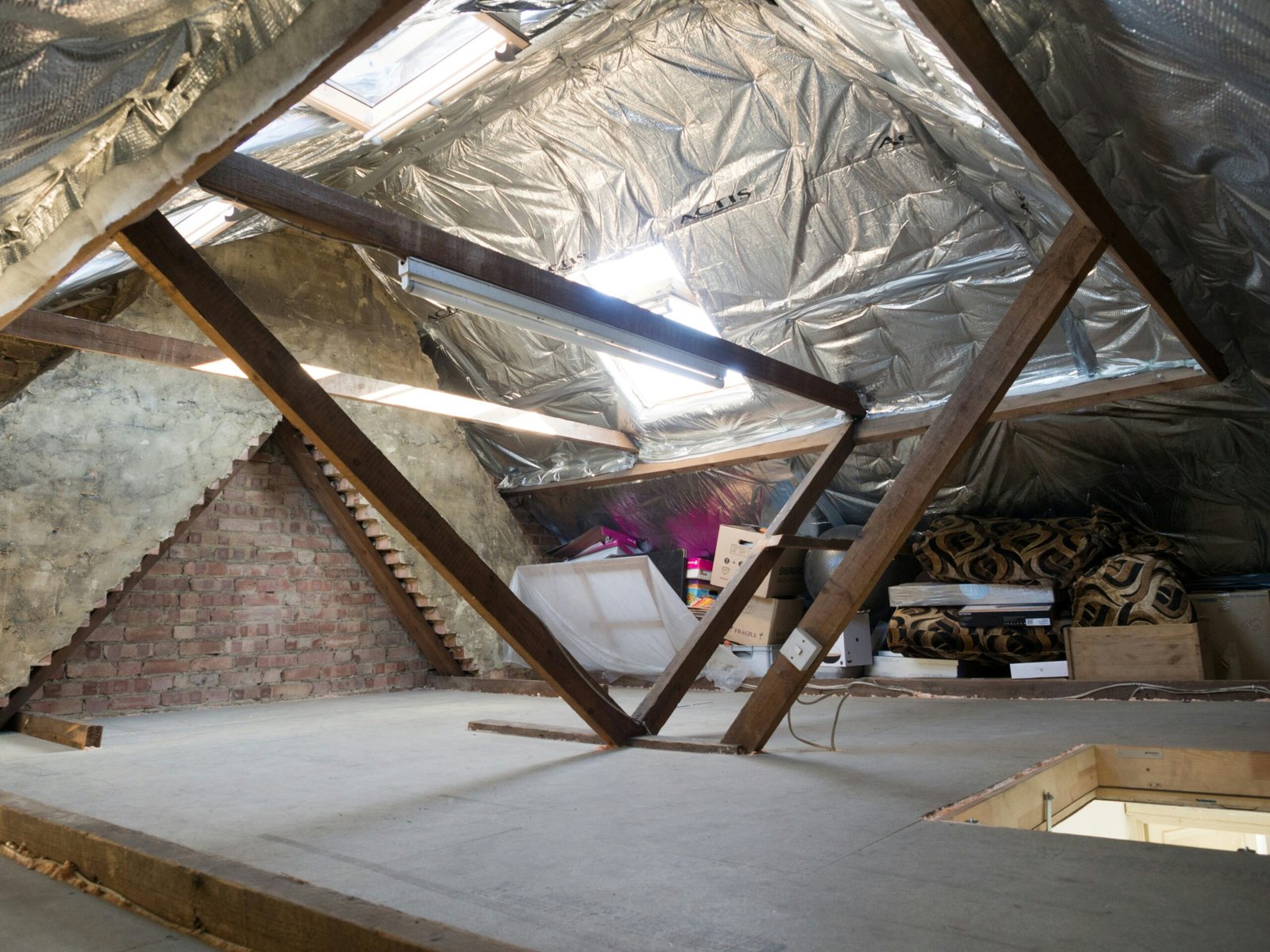 Attic with insulation, beams, and storage.