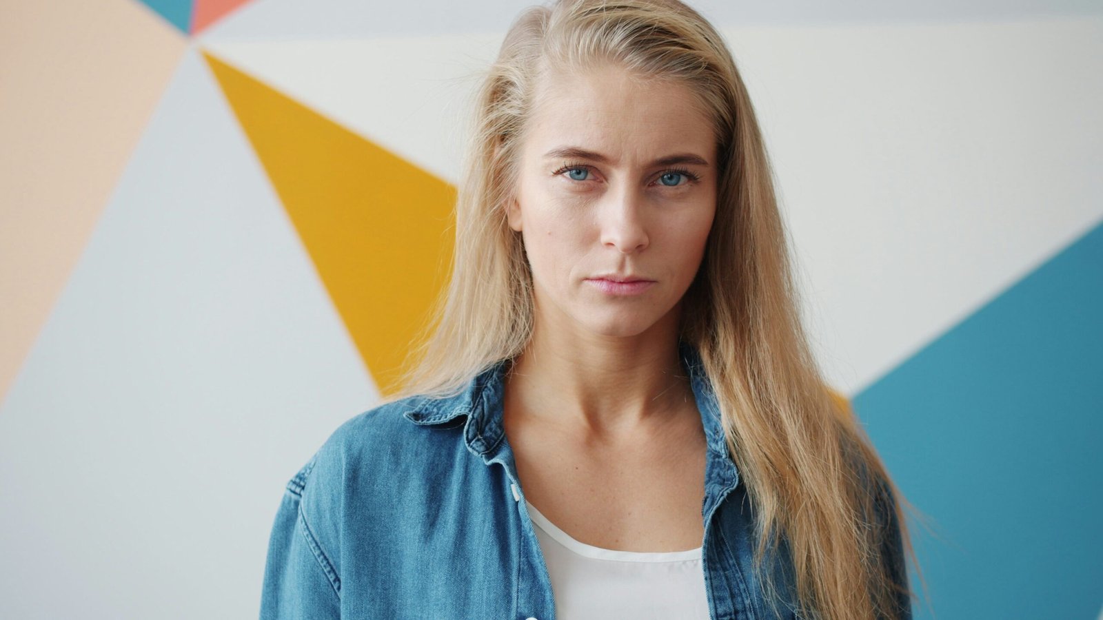 Blonde woman in denim shirt against geometric wall