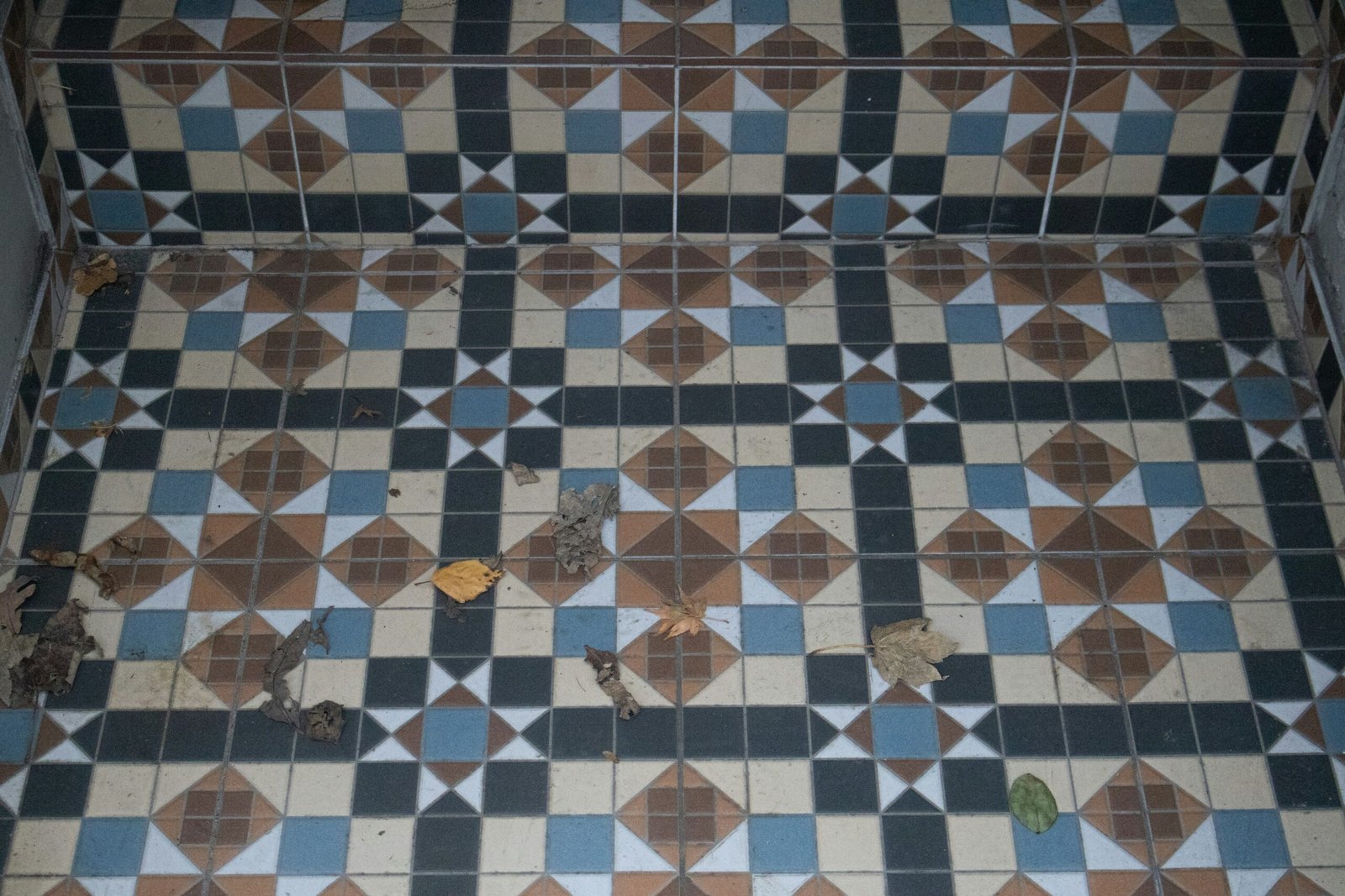 Geometric patterned floor tiles with debris