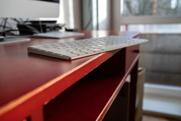 Keyboard is left carelessly on the edge of the desktop and may fall over