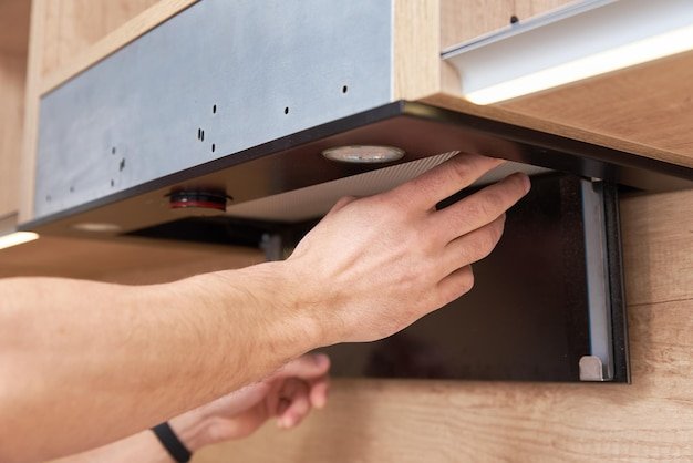 Man repairs hood in the kitchen replacement filter in cooker hood