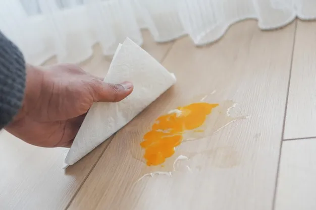A mans hand washing the floor with a tissue cleaning egg spill