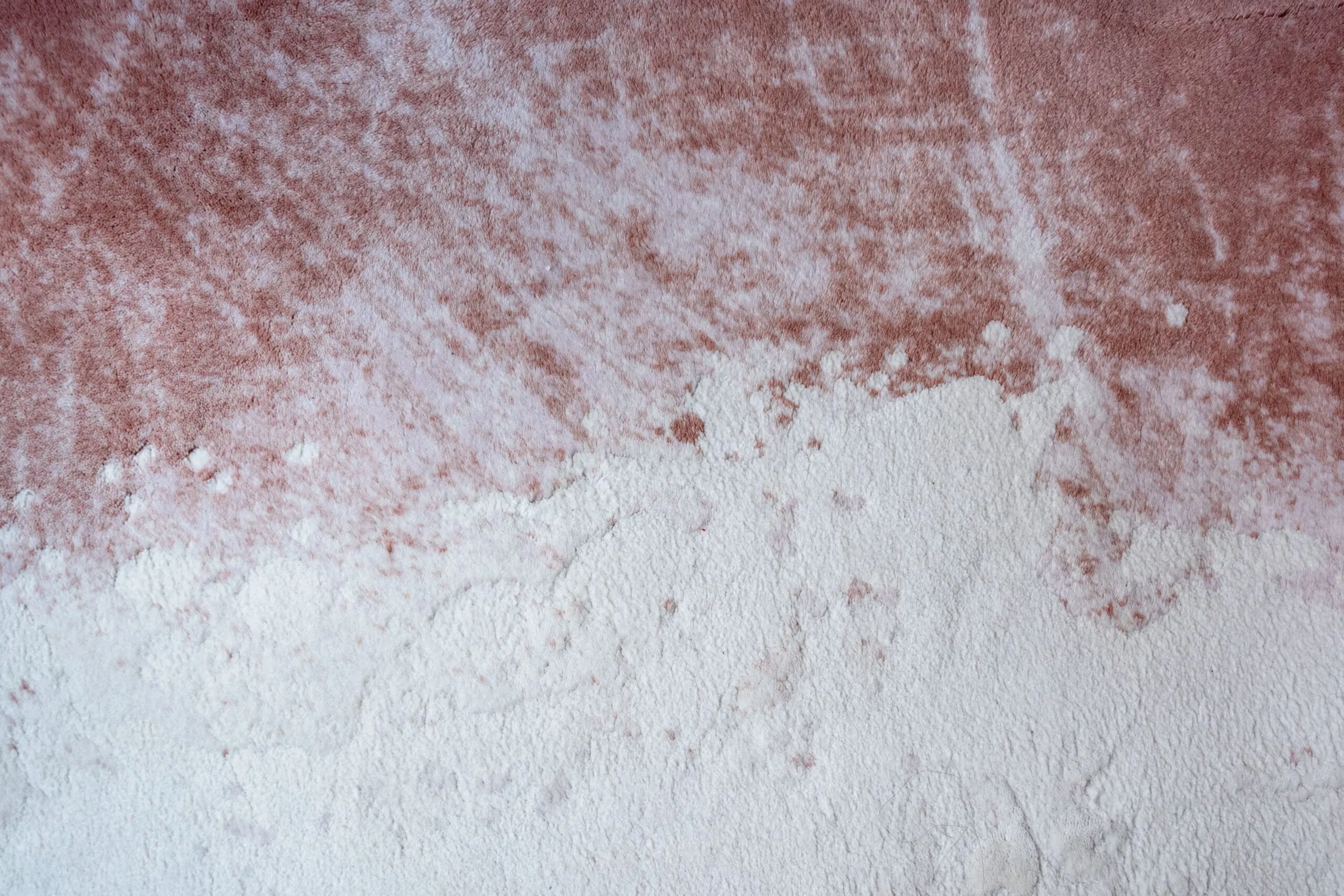 Close-up abstract texture of a pink and white surface resembling plaster or paint.