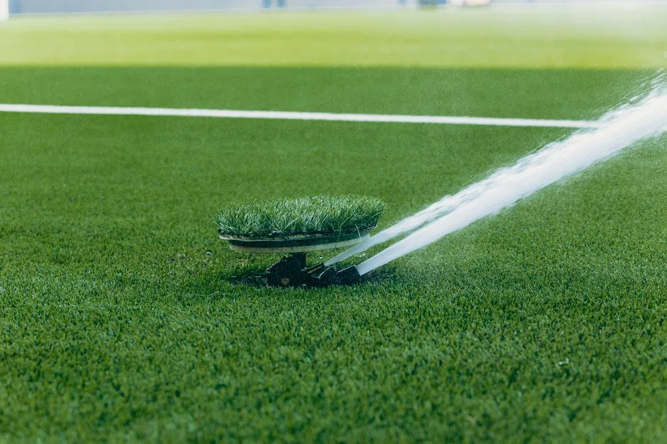 An active sprinkler watering a vibrant green sports field, enhancing the lush grass surface.