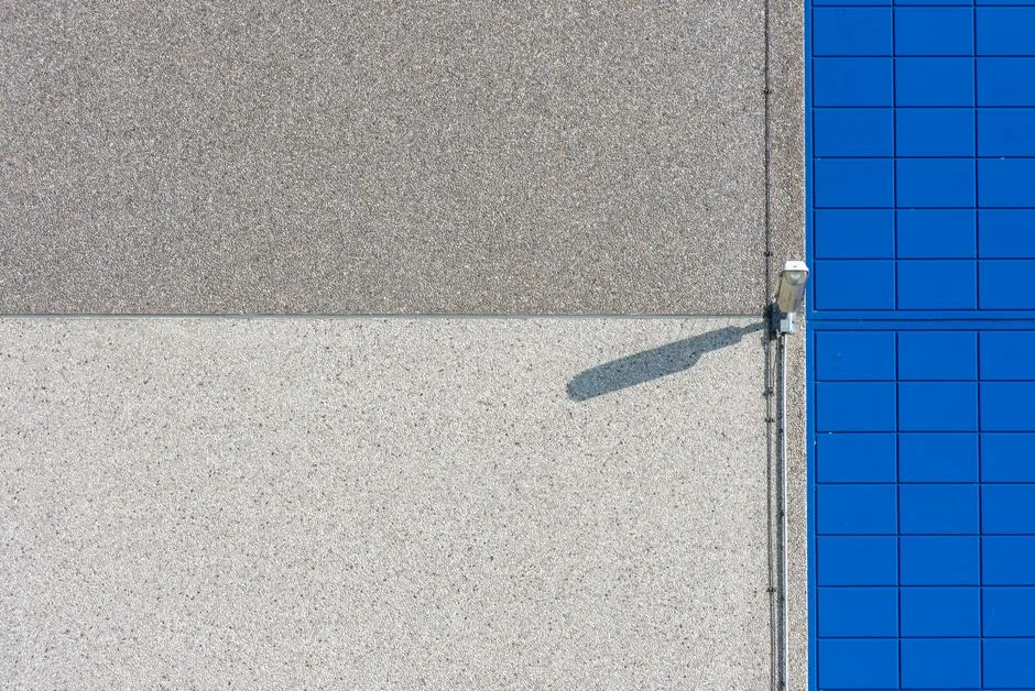 A modern building facade with solar panels and a security light, showcasing clean lines and textures.