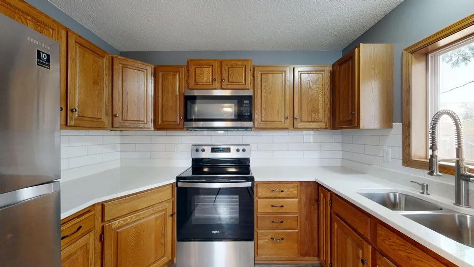 Stylish kitchen featuring wooden cabinets, modern appliances, and large window for natural light.
