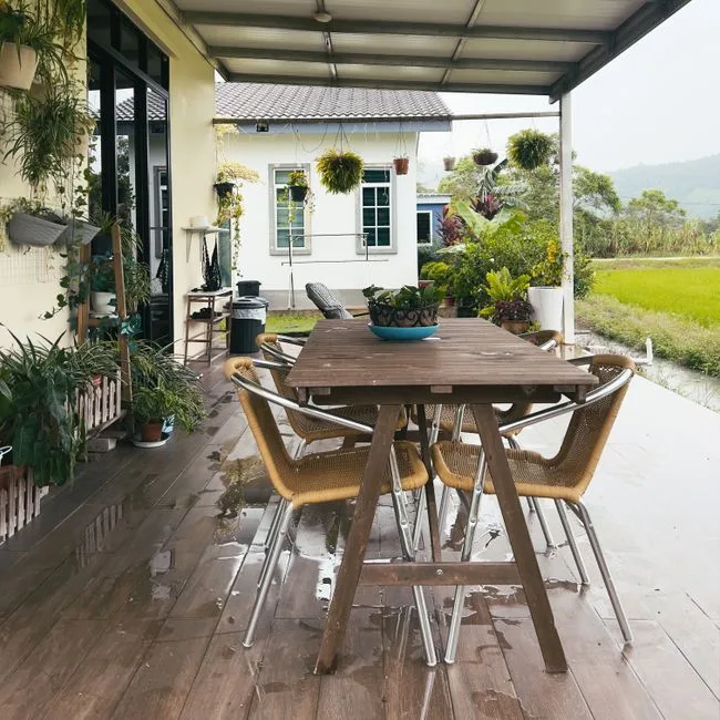 Charming patio with dining setup, lush plants, and countryside view in Balik Pulau, Malaysia.