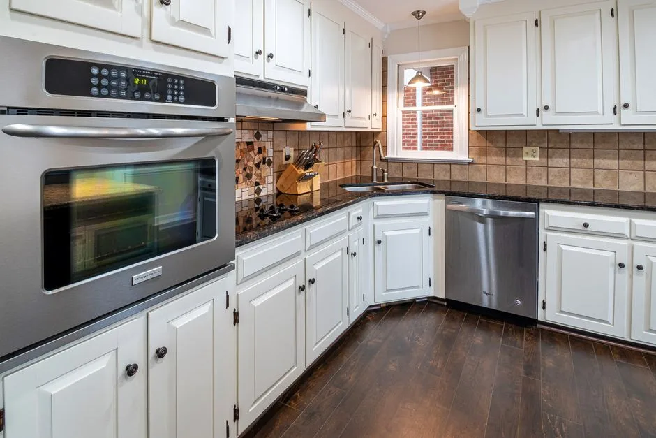 Spacious kitchen featuring white cabinets, stainless steel appliances, and wooden flooring.