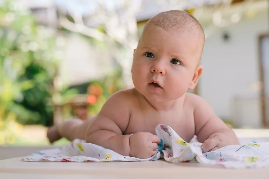 Charming baby on a blanket enjoying tummy time in a sunny outdoor setting, capturing innocence and curiosity.