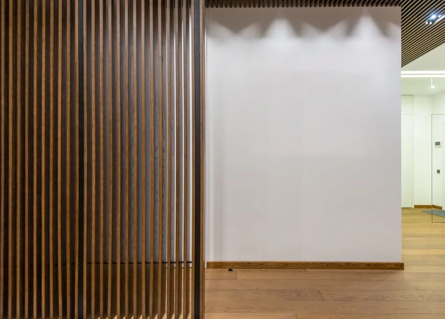 Creative decorative thin wooden partitions placed in spacious corridor of stylish modern apartment with white wall and parquet at home