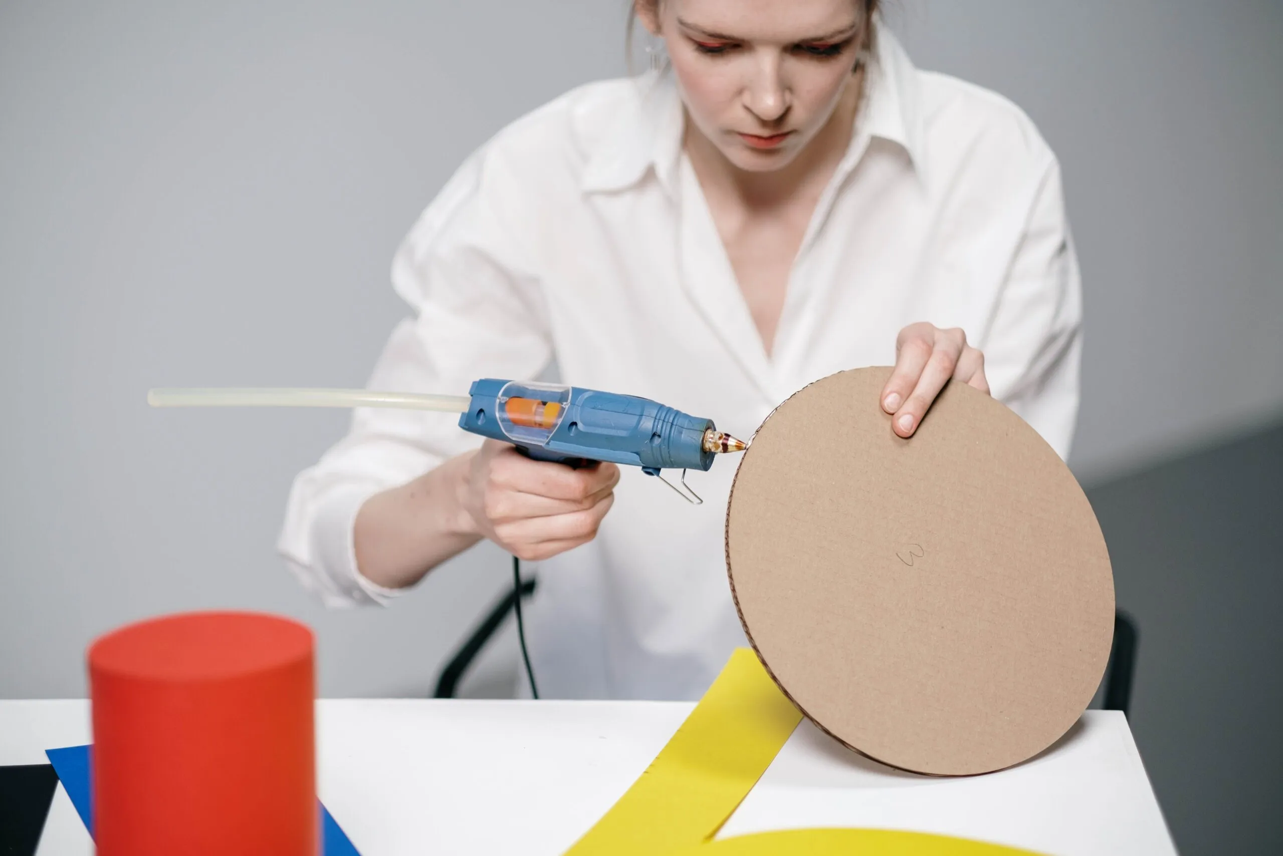 Young woman using a glue gun for a DIY cardboard project.