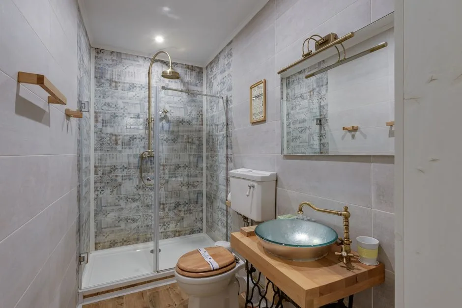 A stylish modern bathroom featuring a glass shower, vessel sink, and wood accents.