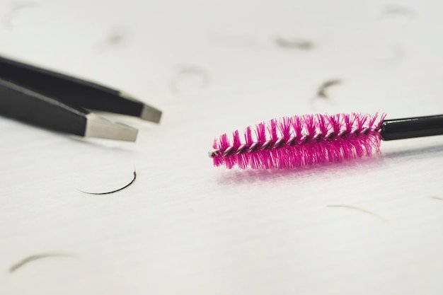 Plucking eyebrows small hair eyebrow brush and tweezers on a white table concept of selfcare focus o...