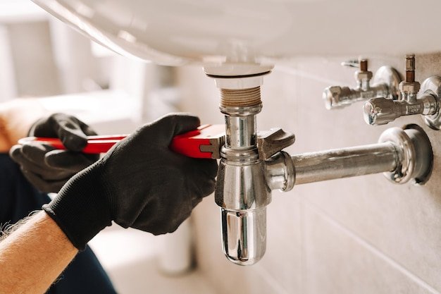 Plumber using adjustable wrench for repairing sink pipe