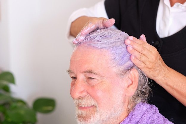 Professional hairdresser apply a special purple color shampoo to remove the yellow color from hairs